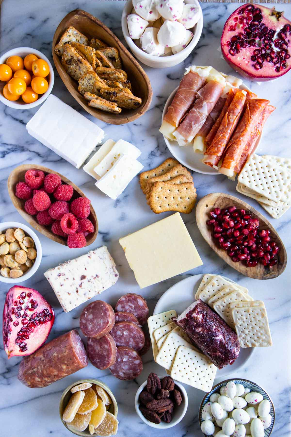 assembling a Christmas charcuterie board on a marble platter