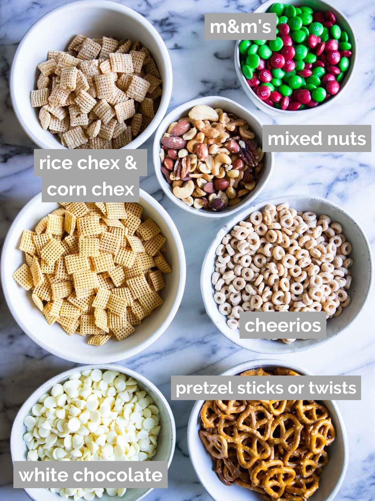 white bowls filled with ingredients to make holiday chex mix