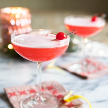 pink lady cocktail in a coupe glass with cherry garnish