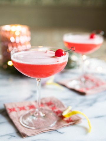 pink lady cocktail in a coupe glass with cherry garnish