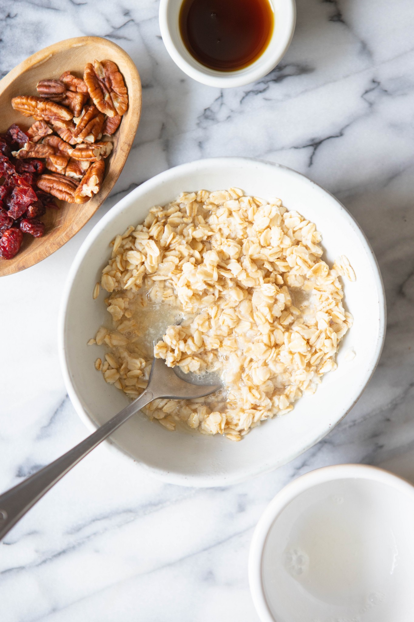 spoon stirring in egg whites into oatmeal in a white bowl