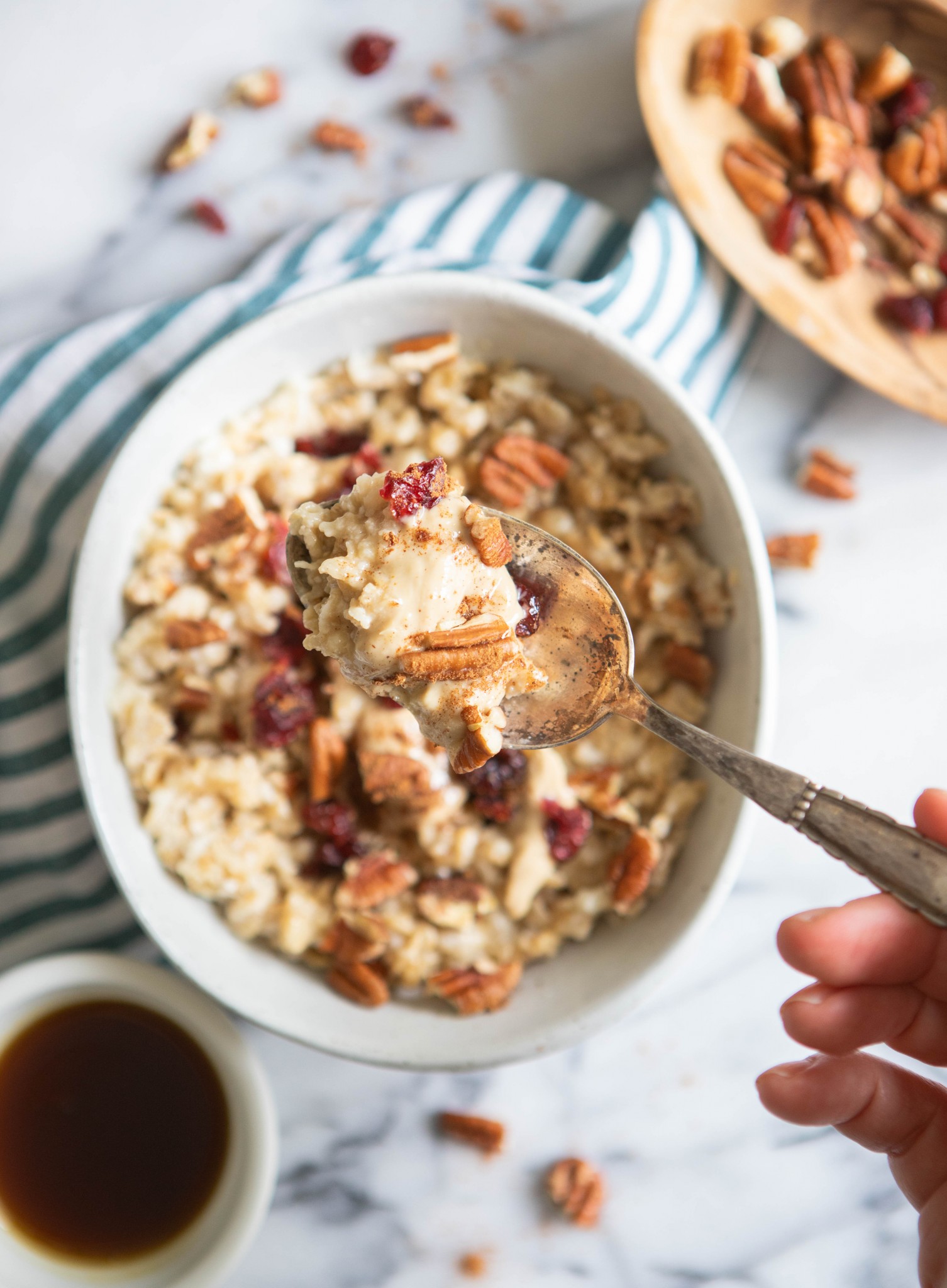 oatmeal with pecans and other toppings in a white bowl with spoon