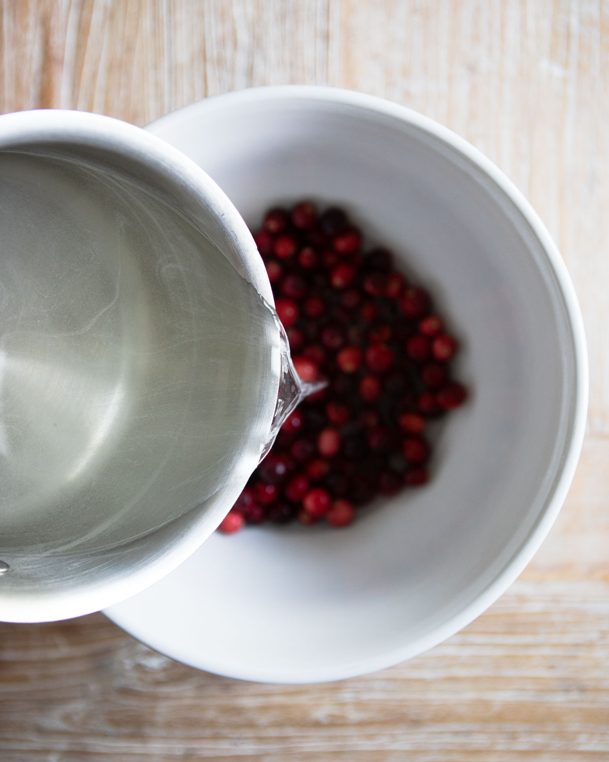 simple syrup being poured over cranberries