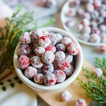 bowl filled with sugared cranberries with Christmas greenery