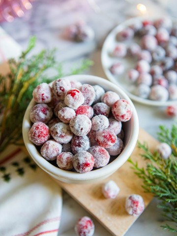 bowl filled with sugared cranberries with Christmas greenery