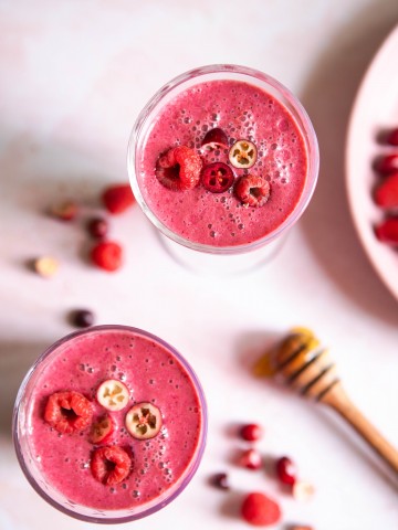 2 glasses filled with a bright pink smoothie on a pink table