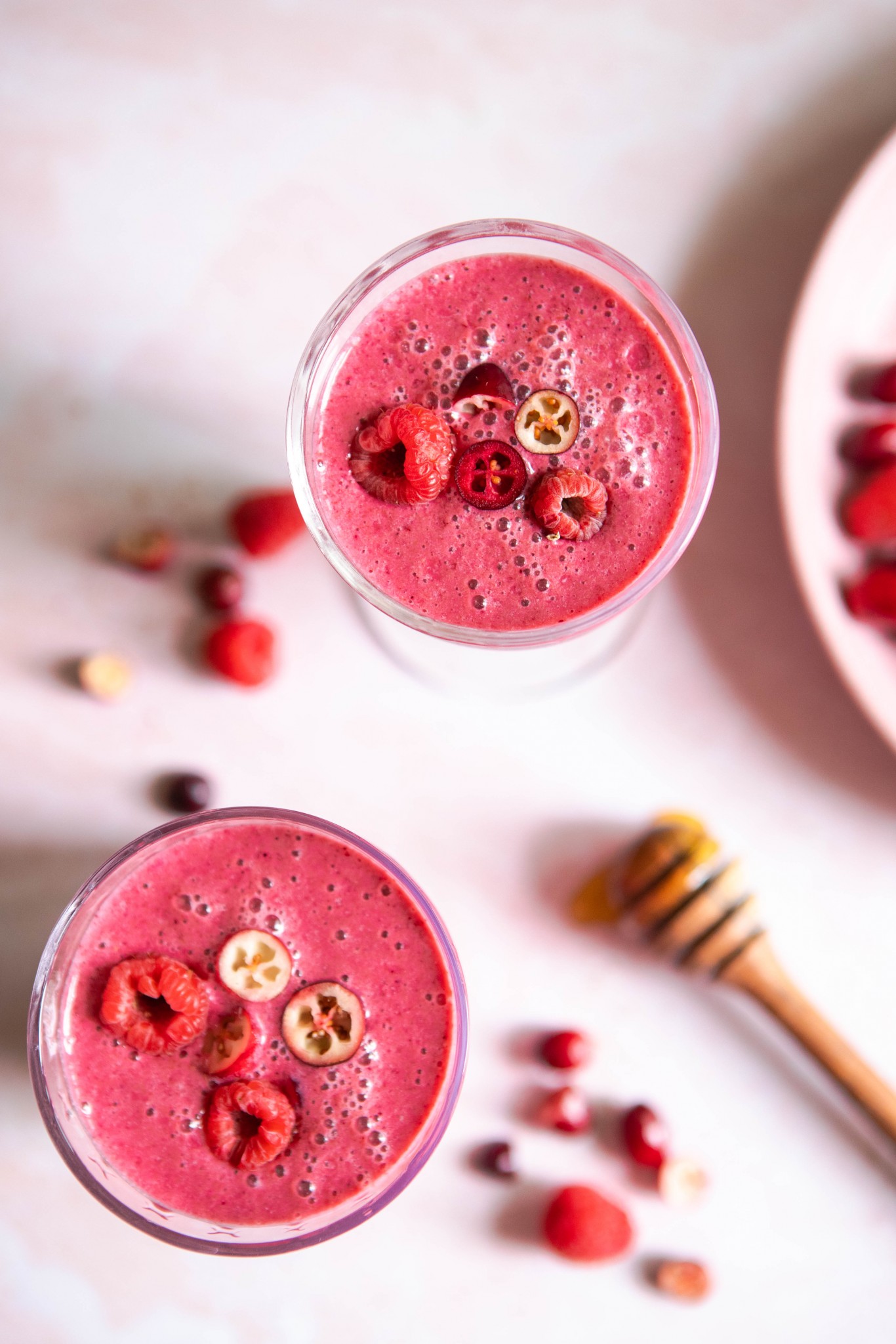 2 glasses filled with a bright pink smoothie on a pink table