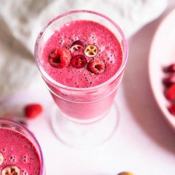 cranberry and berry smoothie in a glass with garnishes