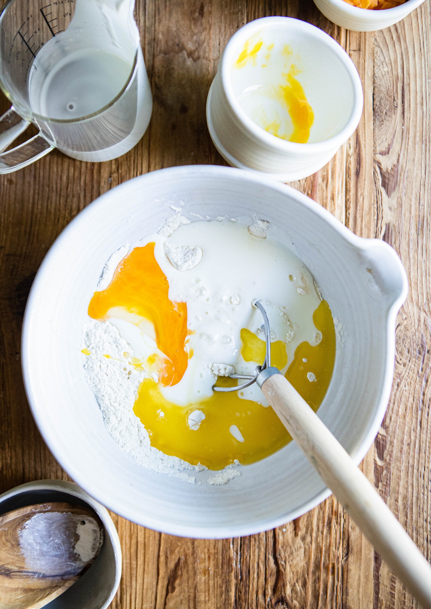 wet waffle ingredients added to dry ingredients in a white mixing bowl