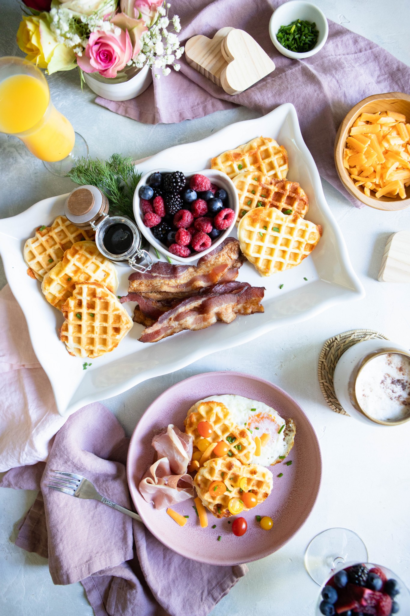 Cheddar and buttermilk waffles on a platter with fruit, bacon and tomatoes 