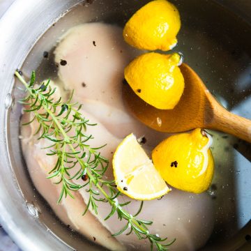 lemon wedges and rosemary in a salt water brine in a stock pot with chicken breasts