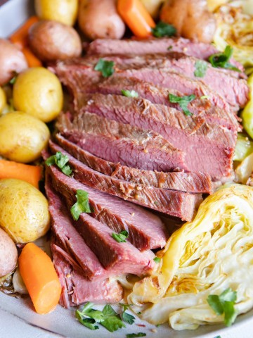 slices of homemade beef brisket nestled in between potatoes, carrots and cabbage