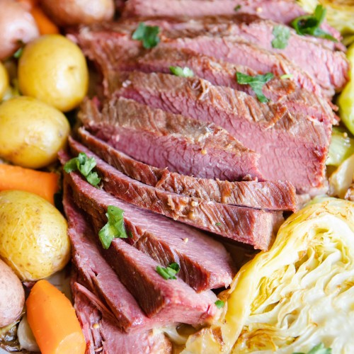 slices of homemade beef brisket nestled in between potatoes, carrots and cabbage