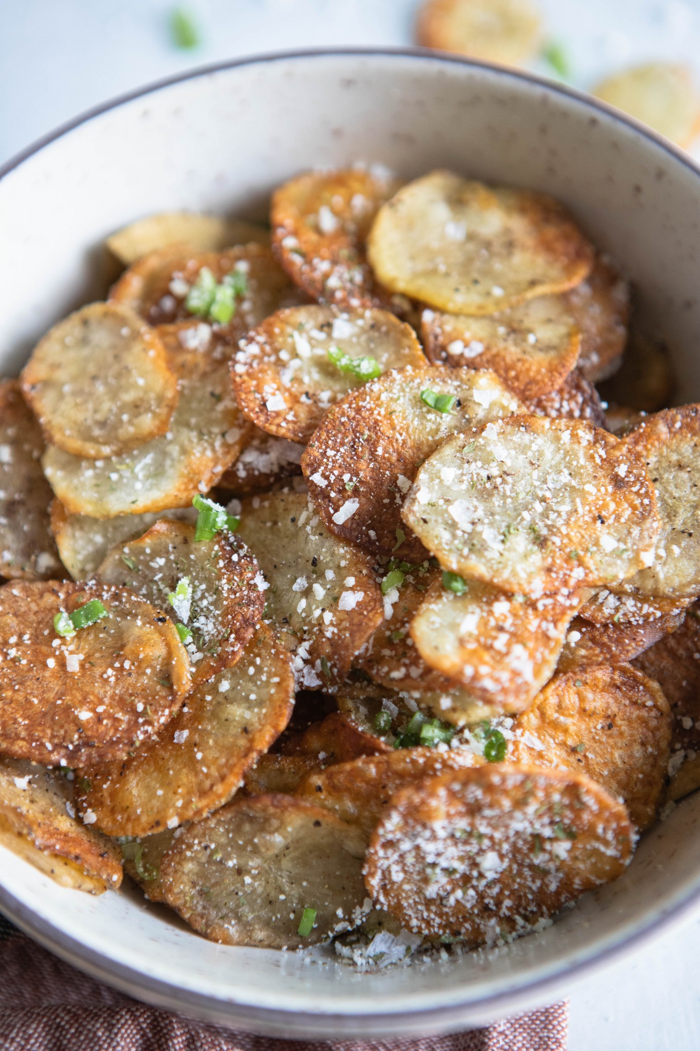 beige bowl holding homemade air fryer potato chips