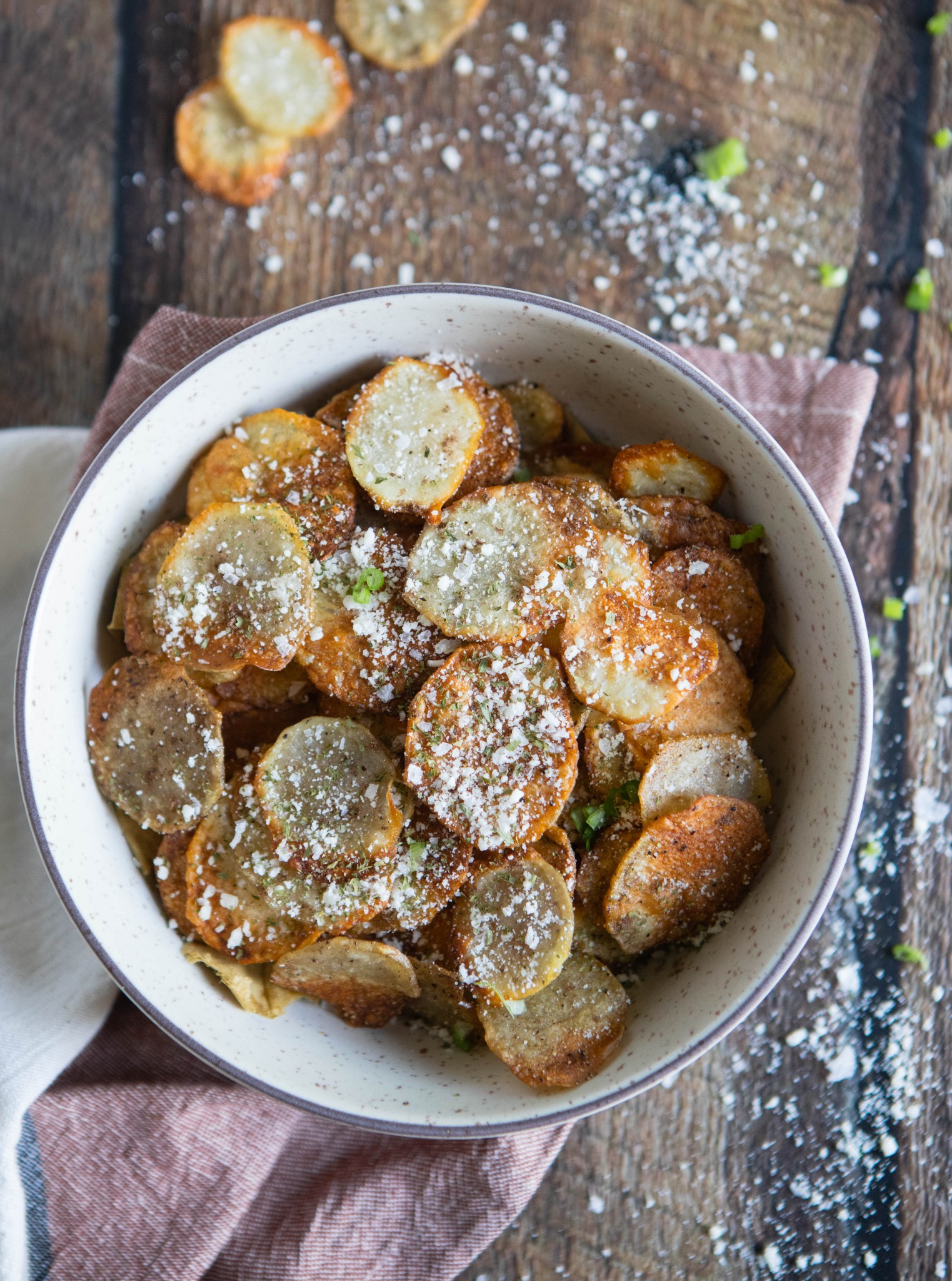 bowl of homemade potato chips made in the air fryer on a wood background