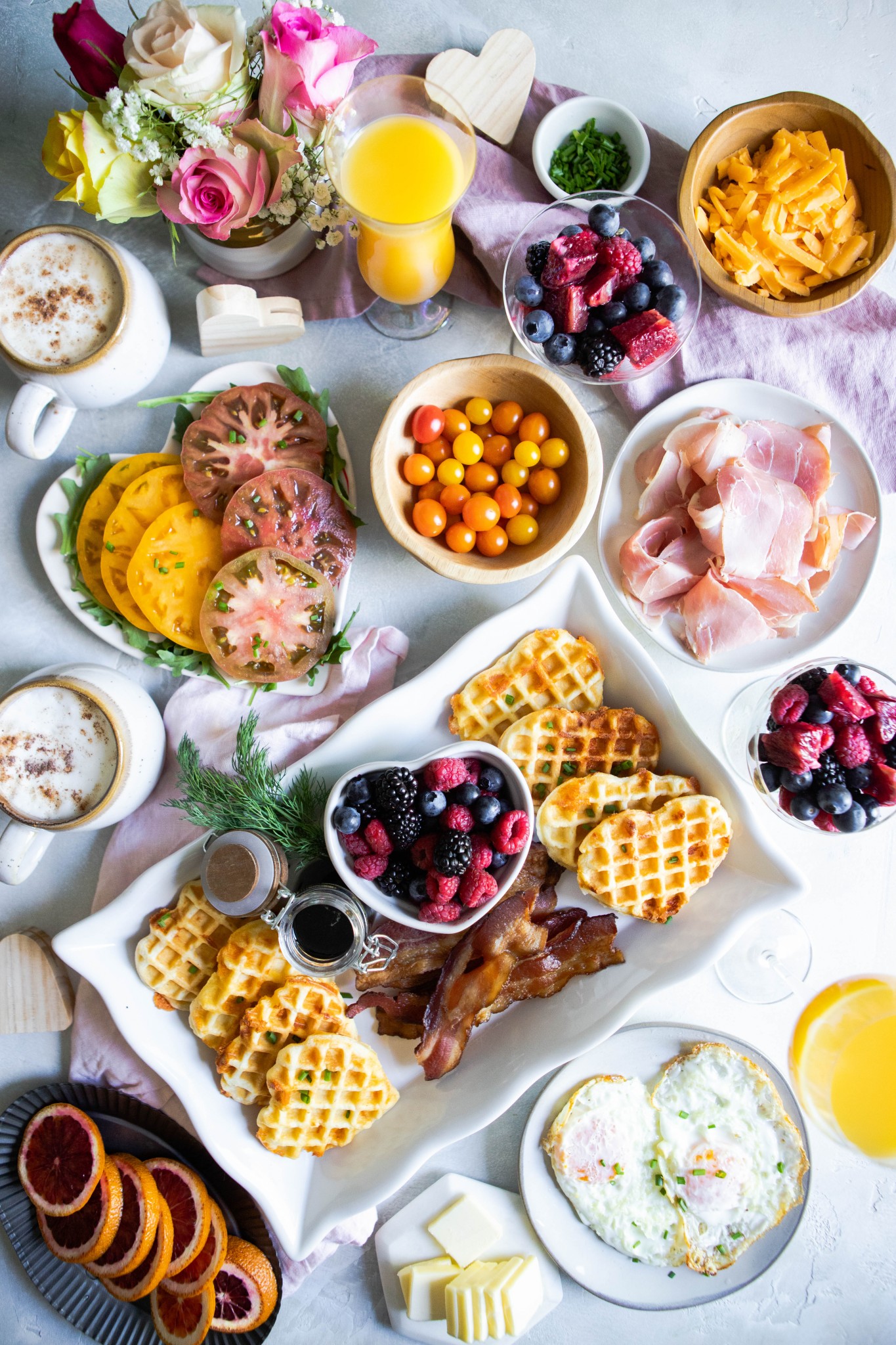 savory waffles breakfast spread with fruit, herbs, tomatoes, bacon and orange juice