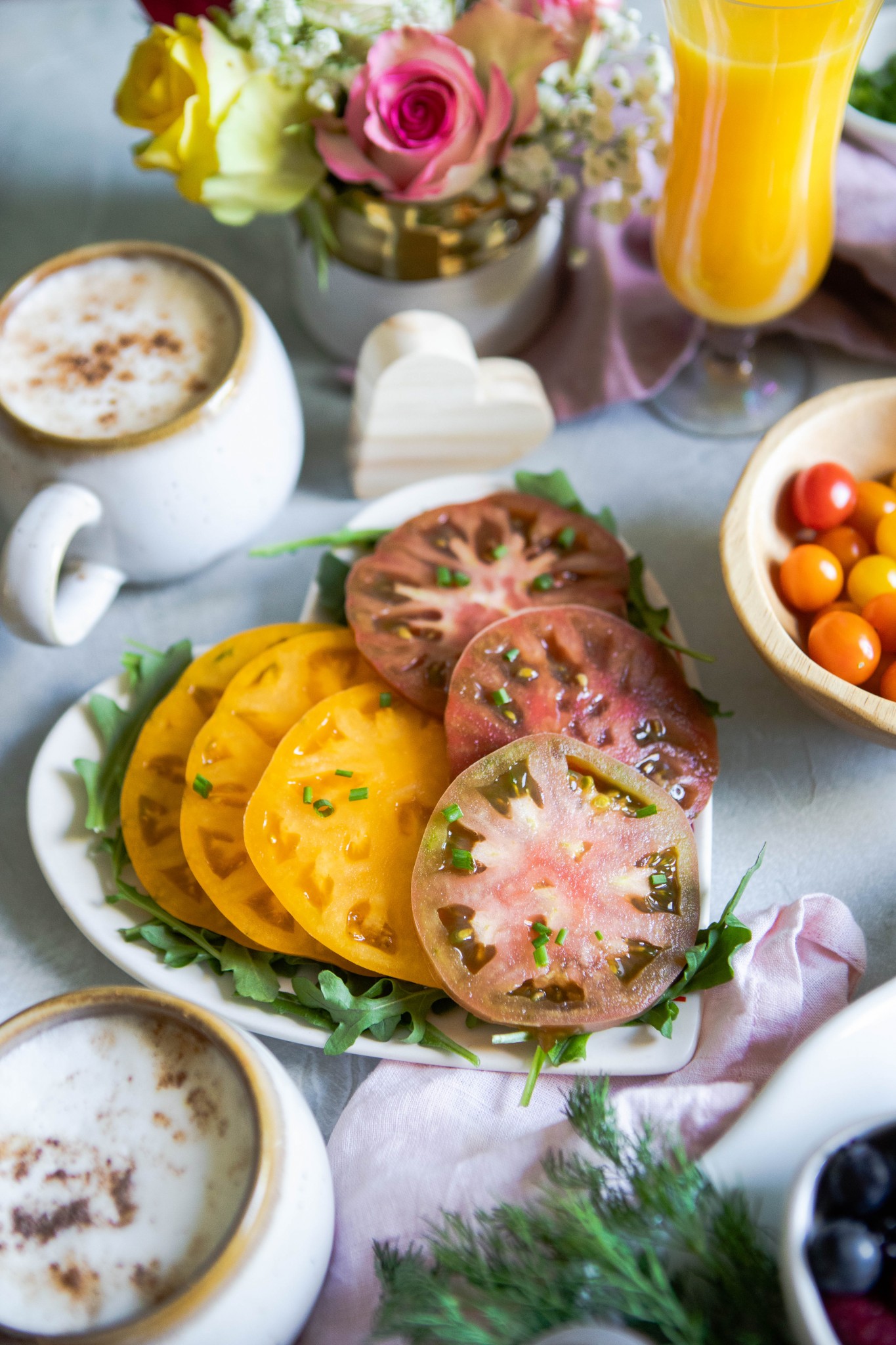 heirloom tomatoes on a heart plate next to a latte