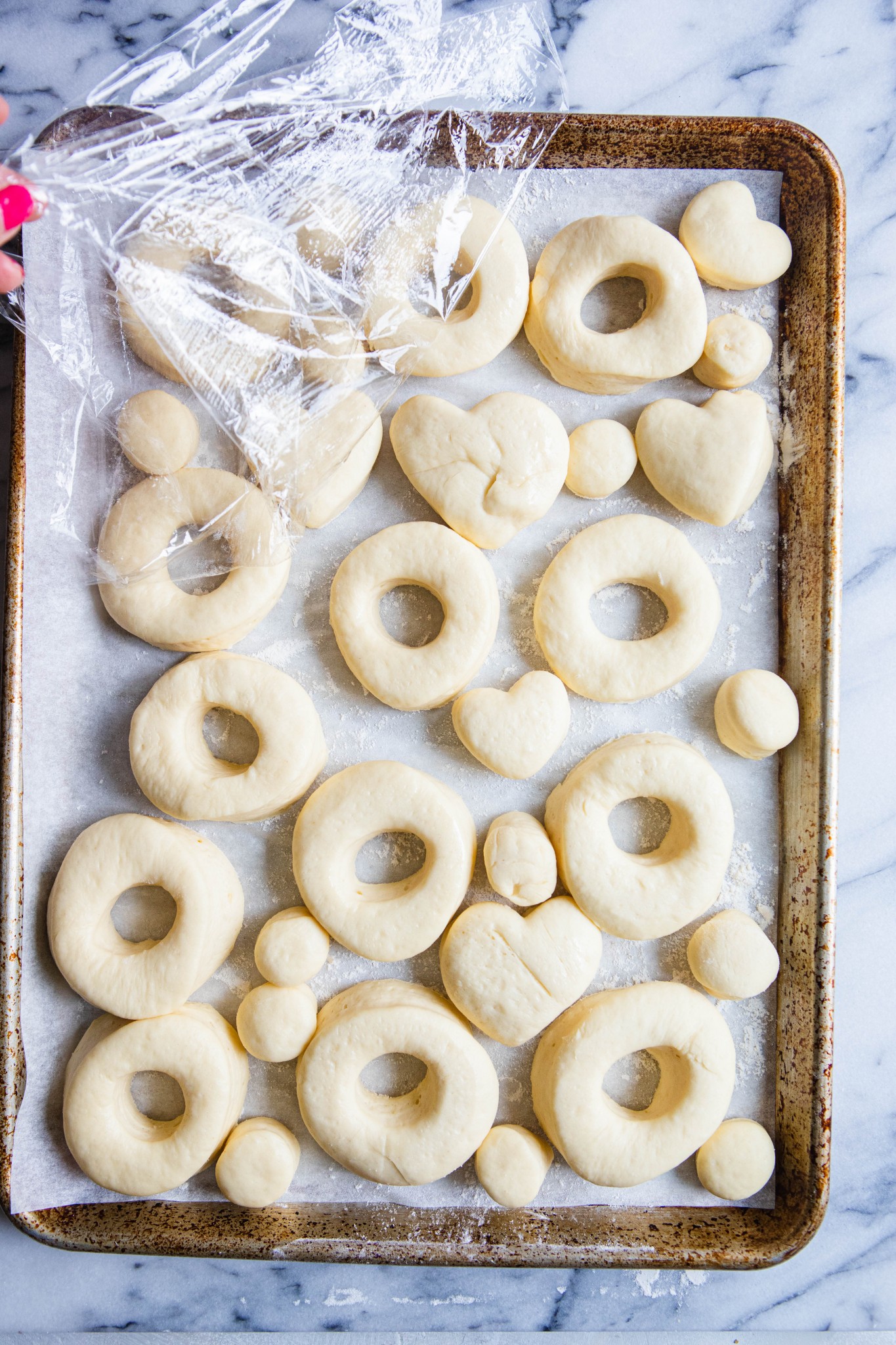 risen donuts on a baking sheet ready to be fried