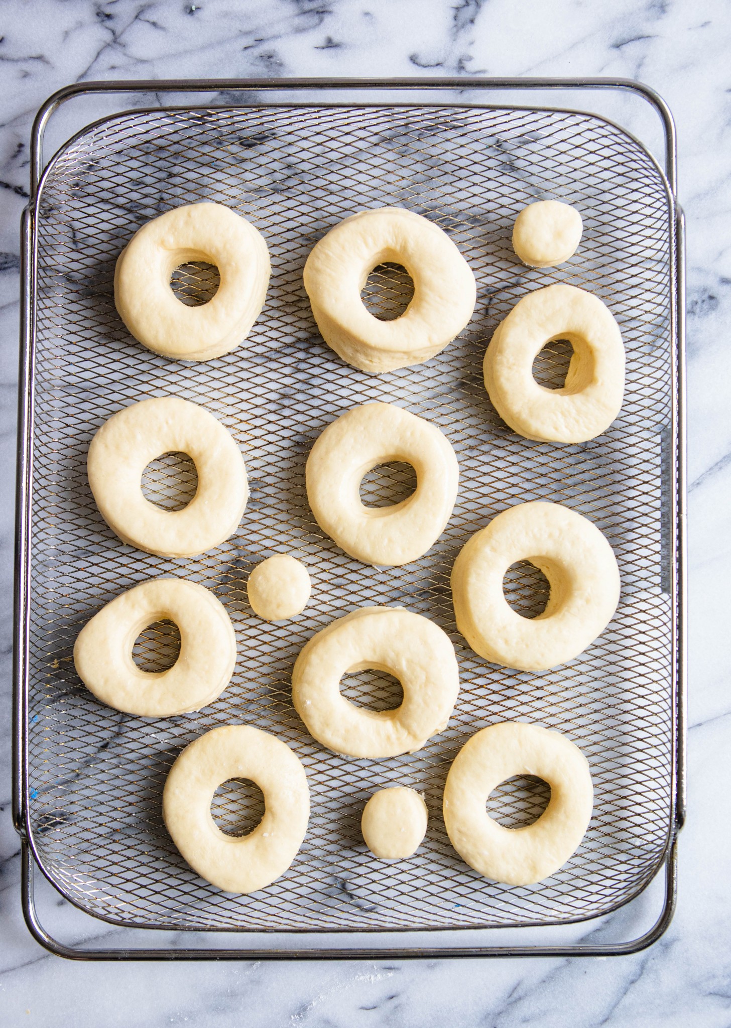 donuts in air fryer basket set against a marble countertop