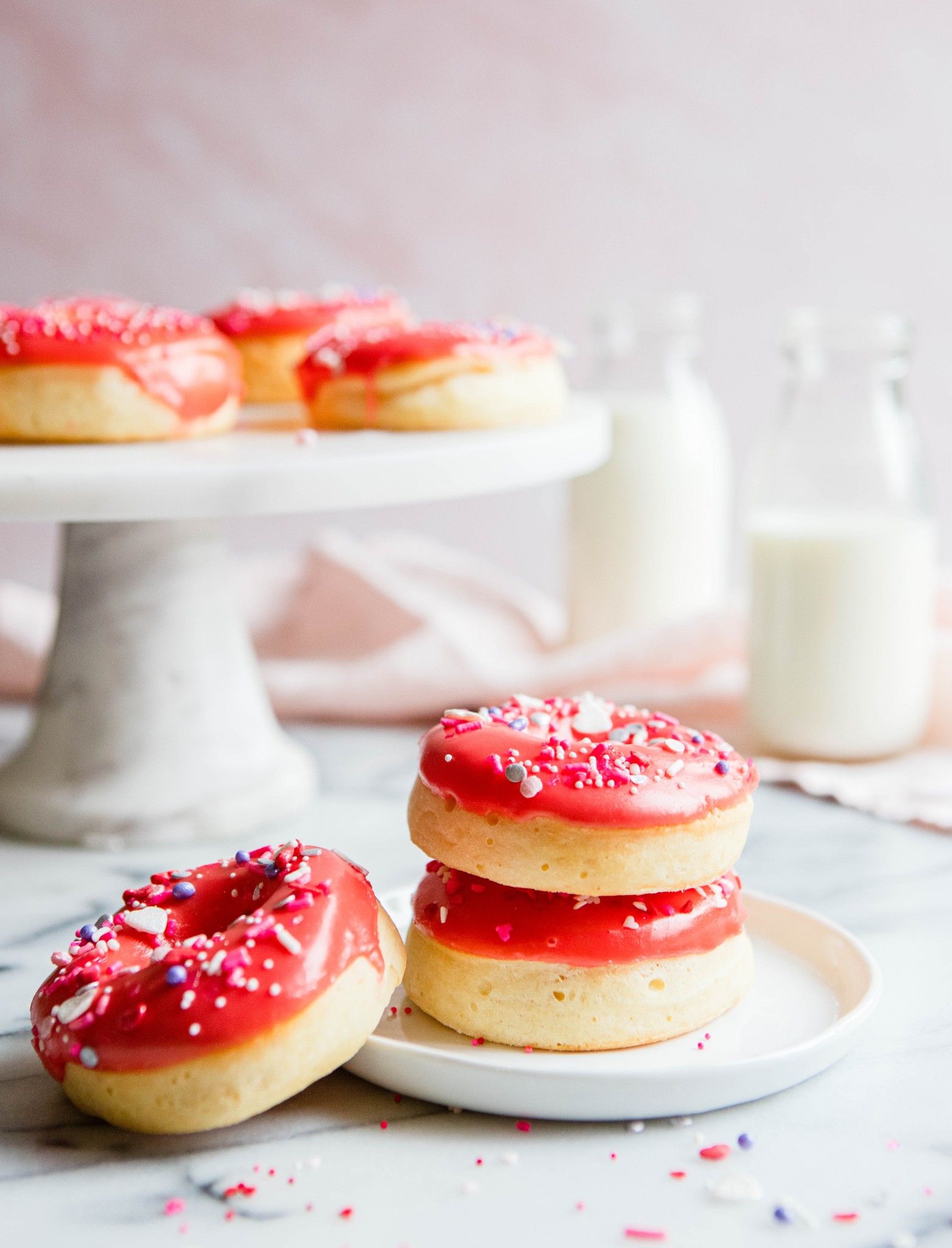 stacked red glazed donuts on a white plate