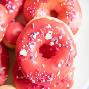 valentine donuts in air fryer sprinkled with red glaze and heart sprinkles