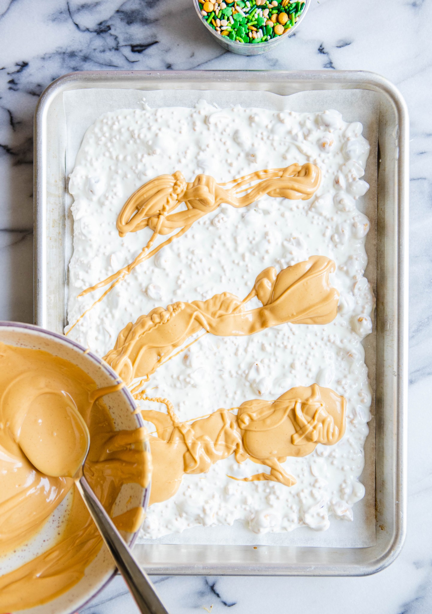 melted peanut butter chips spread over ingredients for a sheet pan