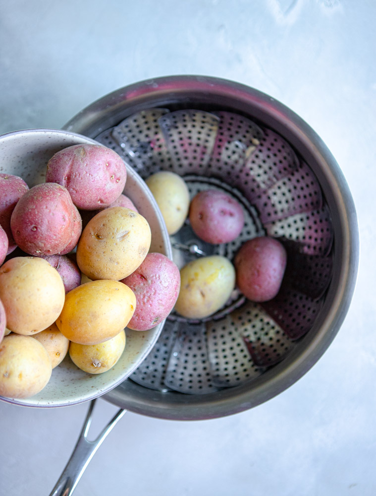 baby red and white potatoes being placed in a steamer basket