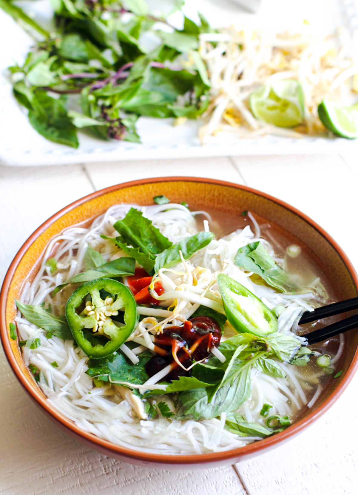 bowl of chicken pho ga with hoisin sauce and sriracha