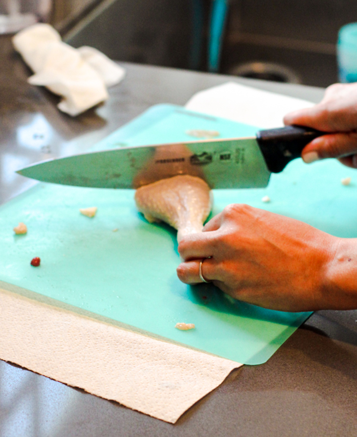 woman cutting a slice into a raw piece of chicken