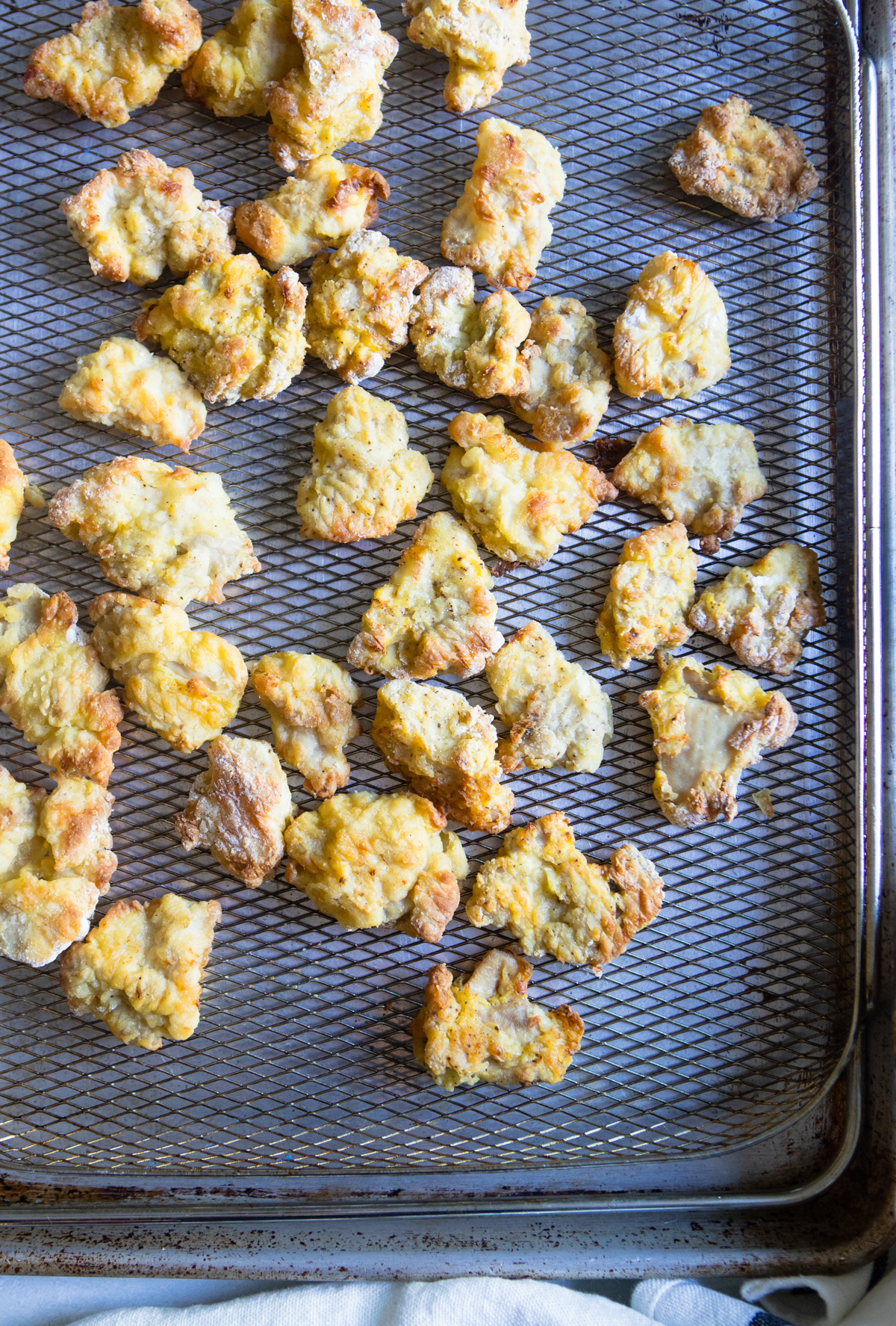 fried chicken thigh pieces set on an air fryer basket tray