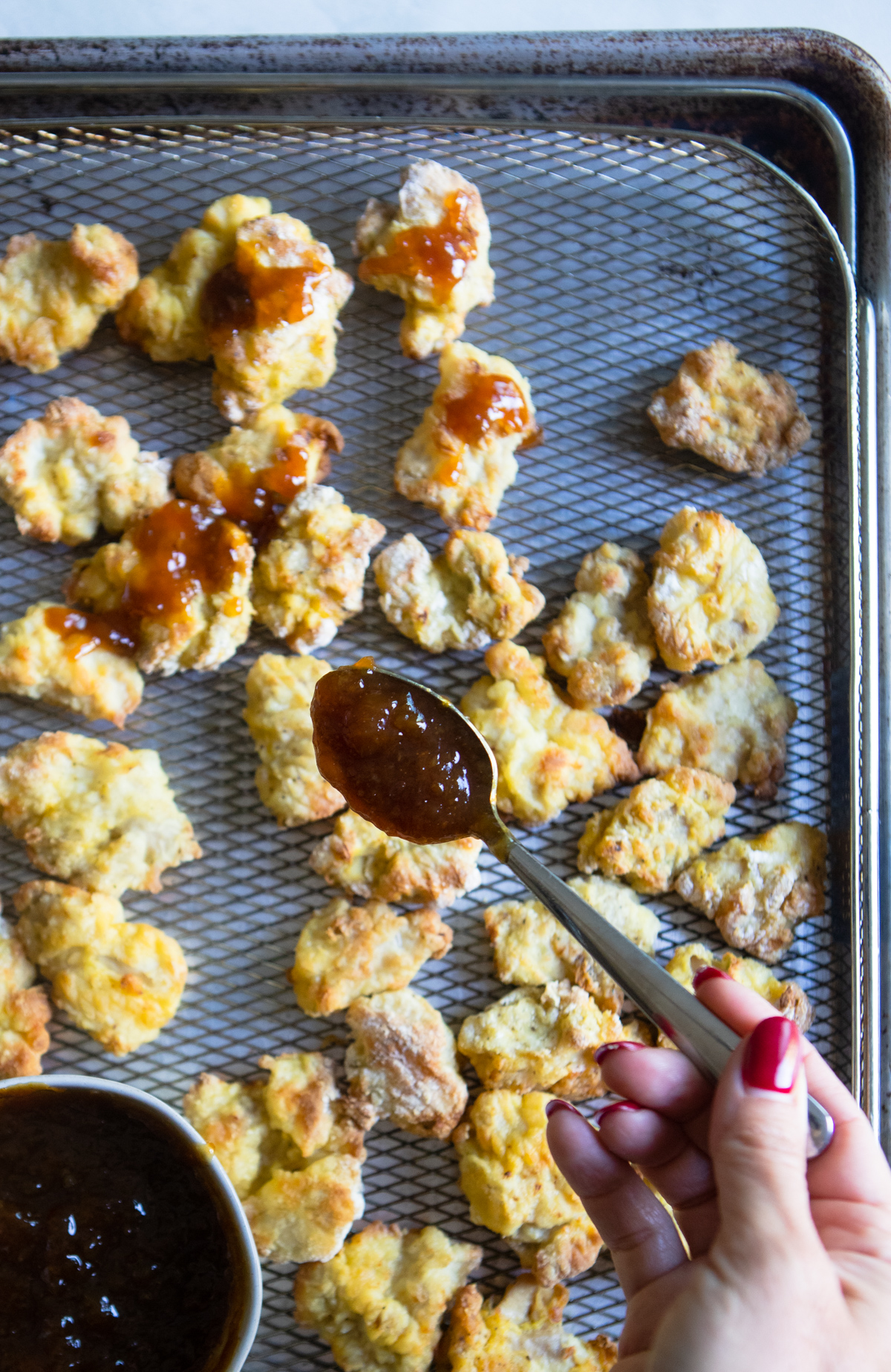 air fried chicken in a tray and orange sauce being drizzled on top