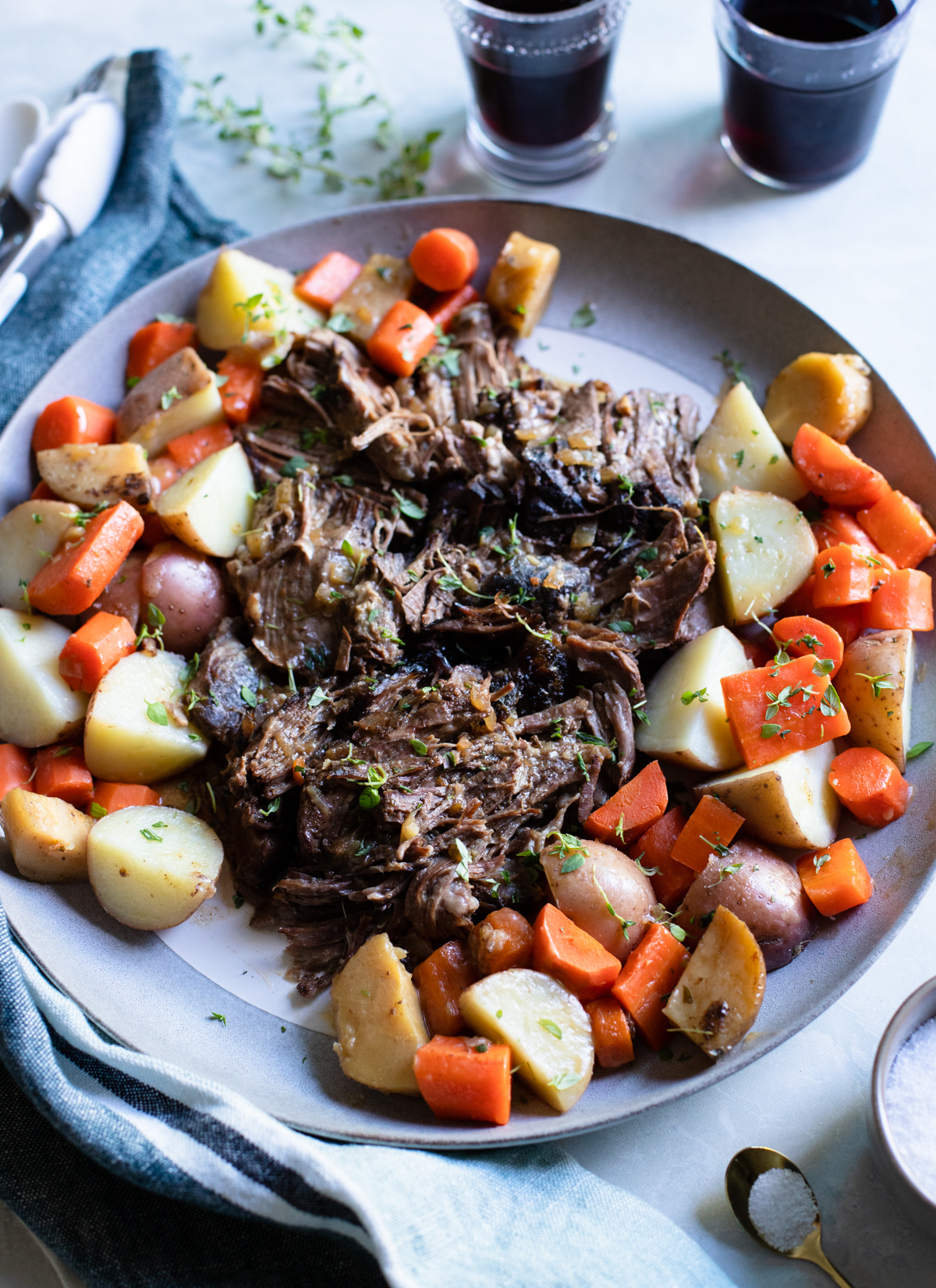 gray round plate stuffed with a top round roast made in the slow cooker surrounded by vegetables