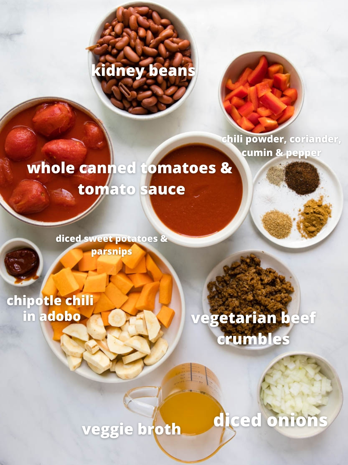 ingredients for vegetarian chili laid out in white bowls against a marble backdrop