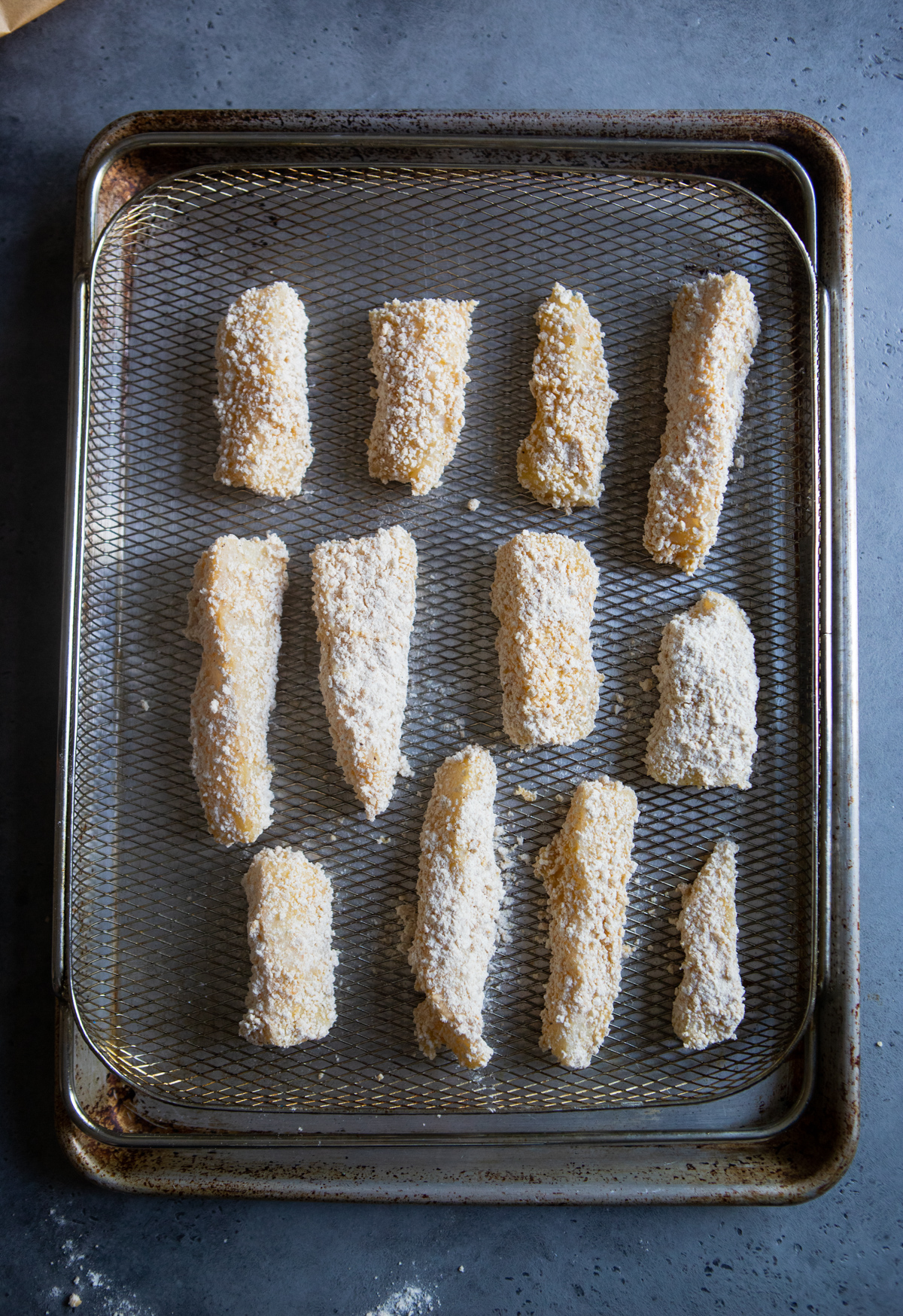 raw fish sticks breaded and placed on an air fryer basket and ready to be placed in the air fryer