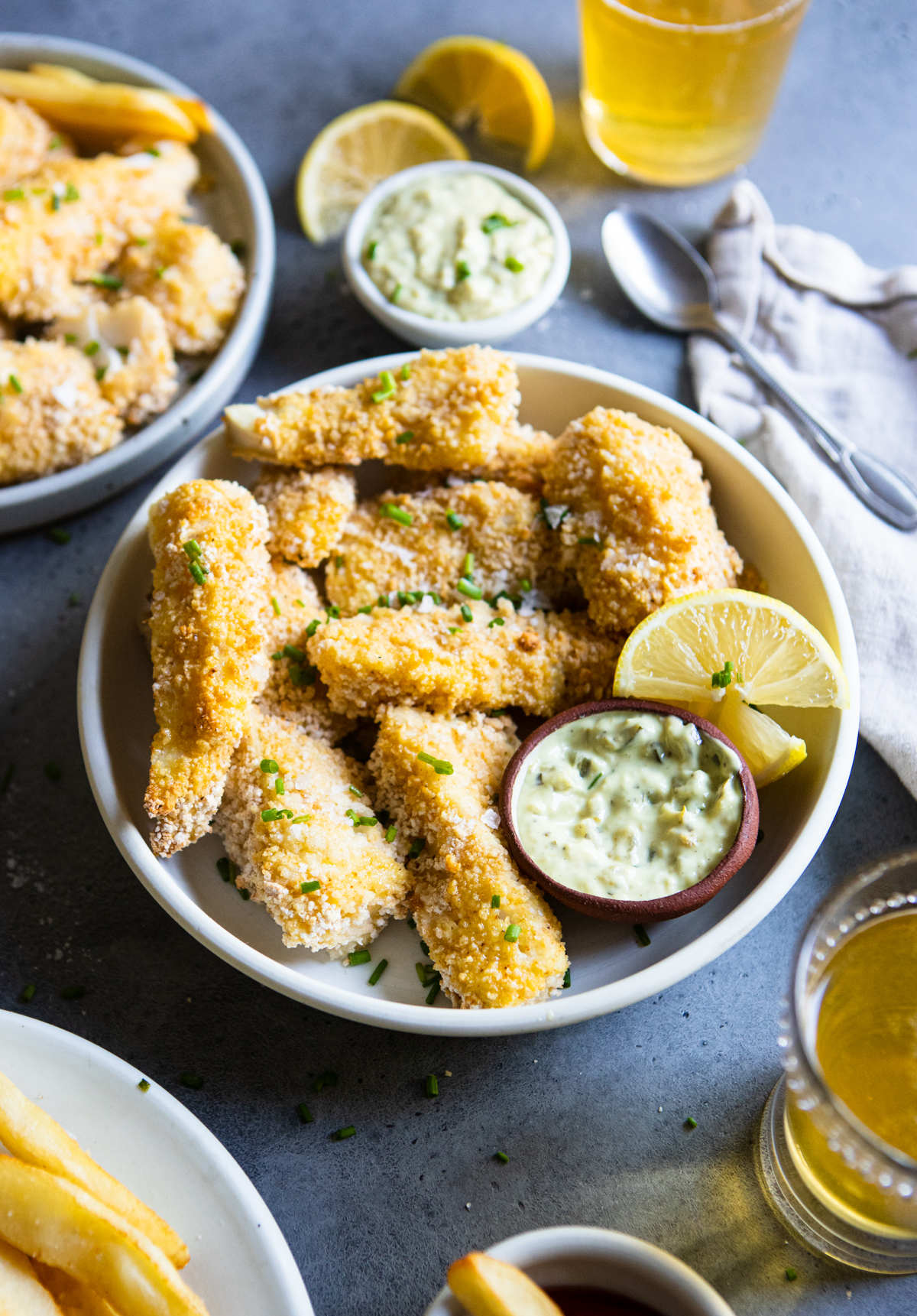 round white plate filled with fish sticks and french fries and lemon garnishes