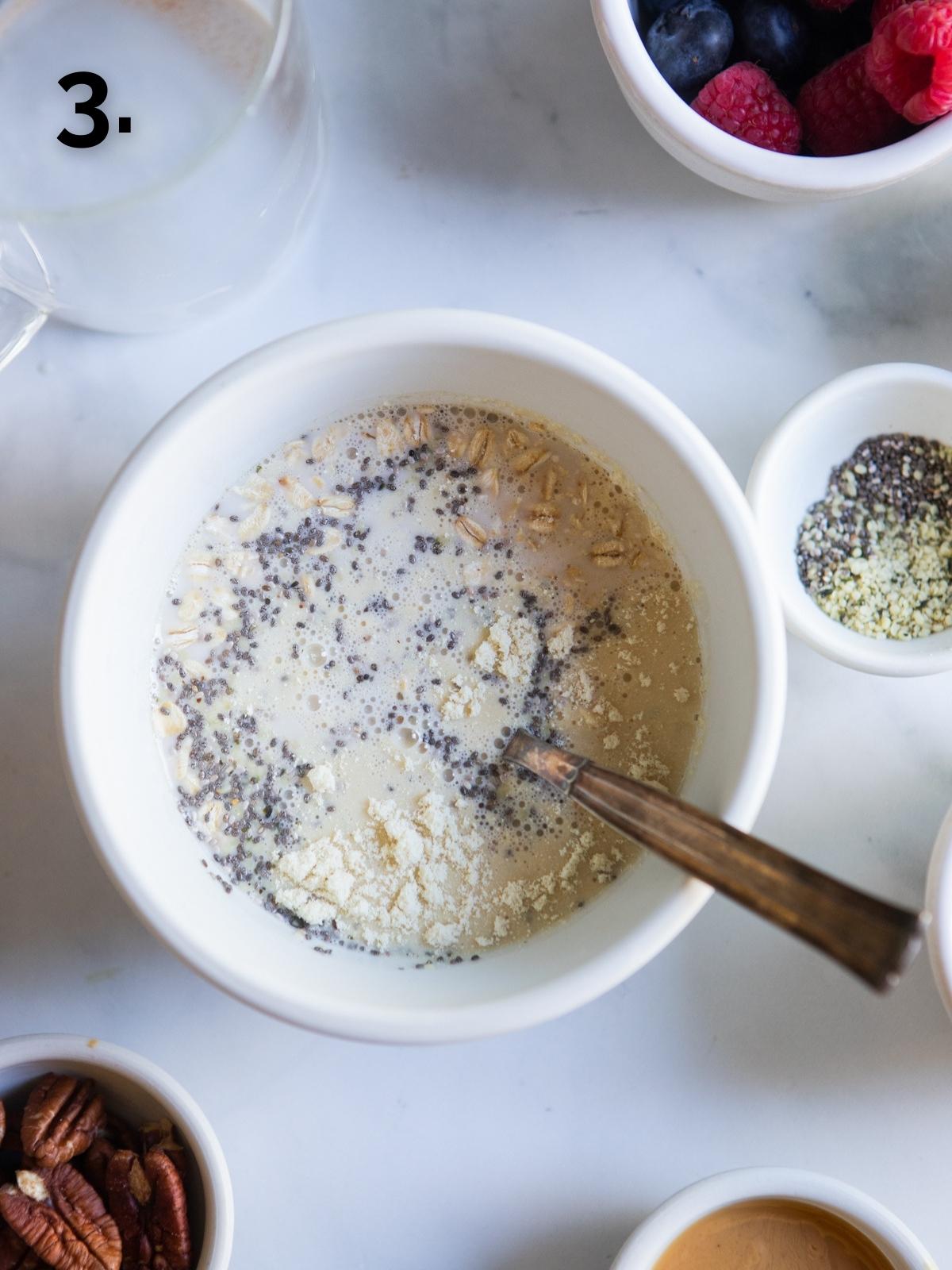 instructional photo of white bowl with ingredients stirred to show how to make overnight oats with protein powder 