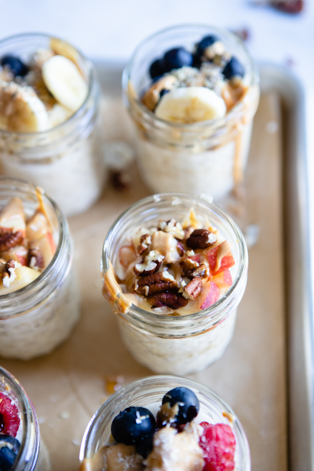 6 mason jars filled with overnight oats with protein powder and topped with fruit and nuts