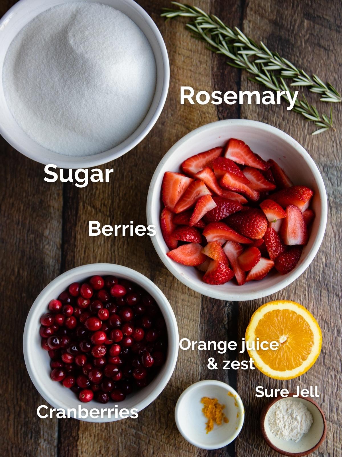 white bowls filled with cranberries and strawberries on a wood background 