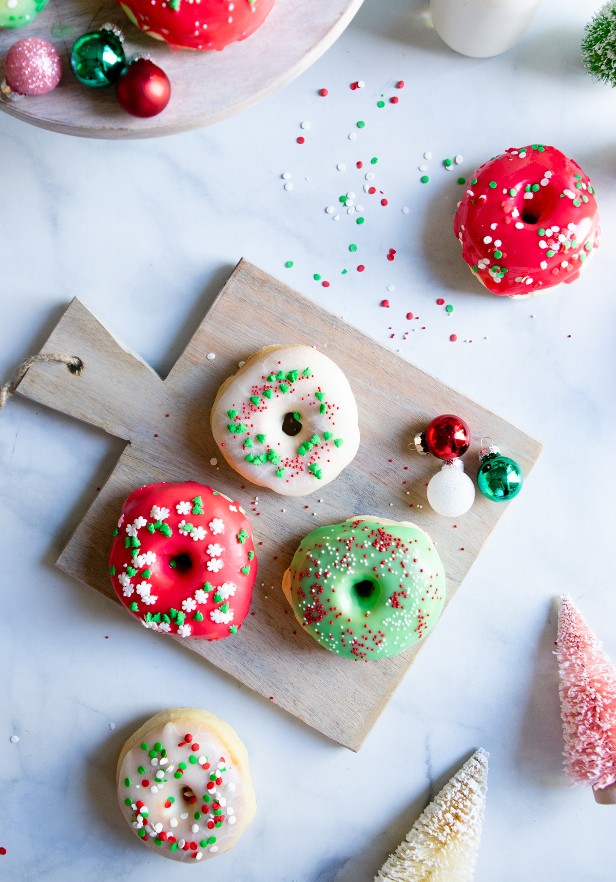 donuts glazed with red and green frosting and topped with holiday sprinkles 