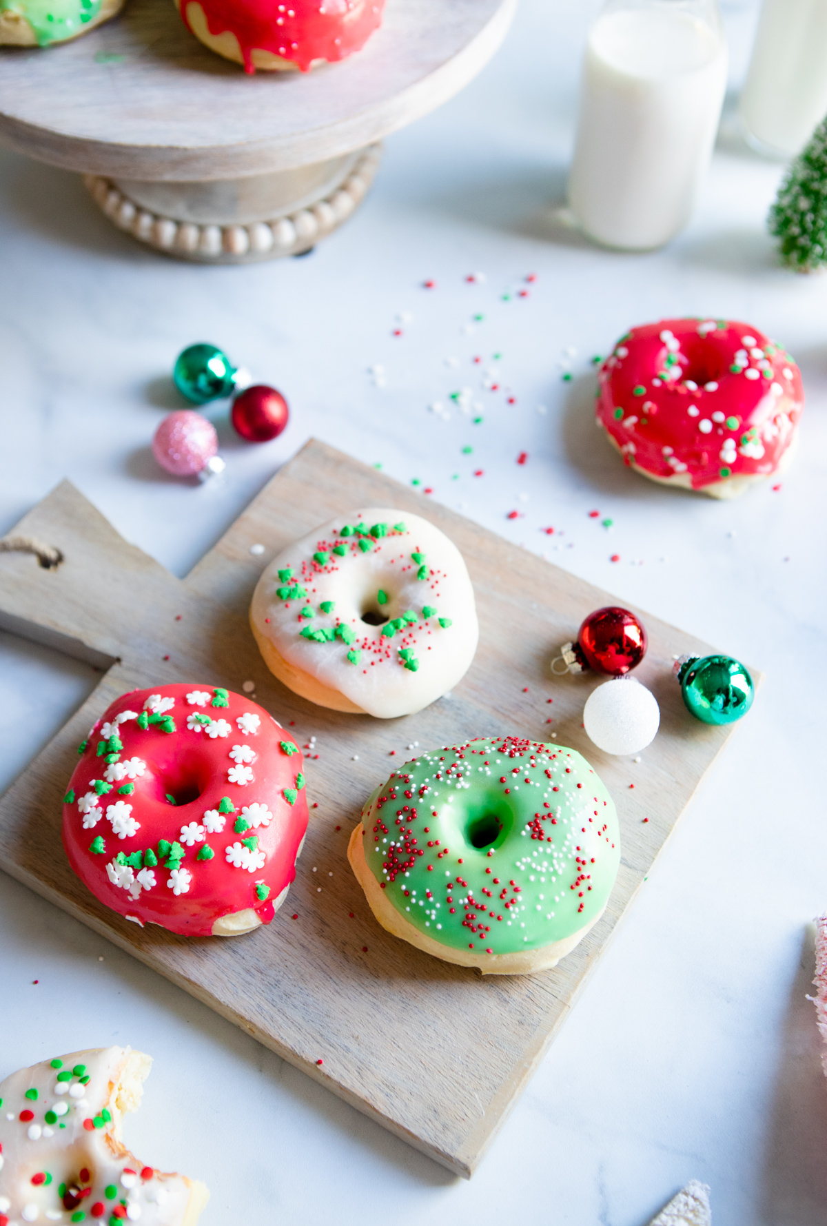 red and green frosted Christmas donuts on a wooden board