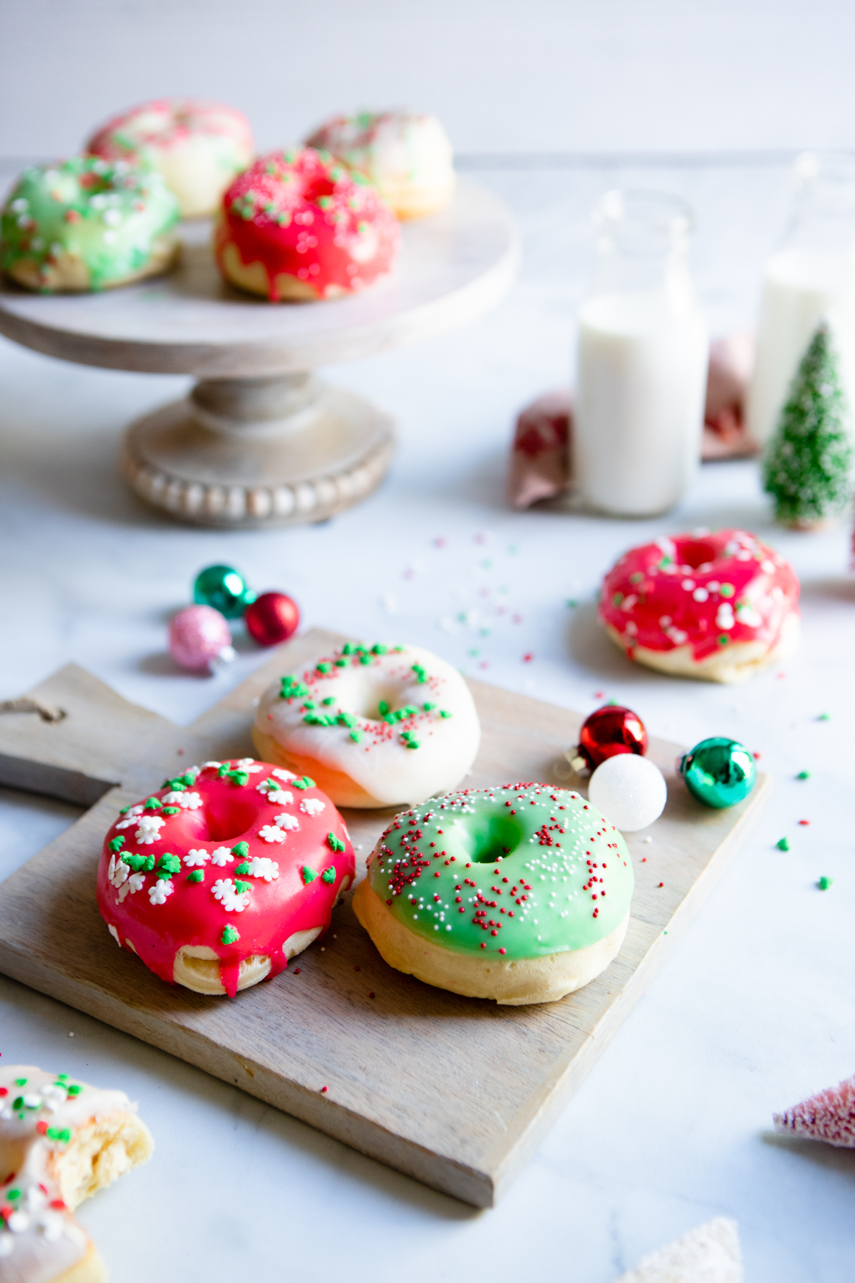 red white and green Christmas donuts with holiday sprinkles on a marble board