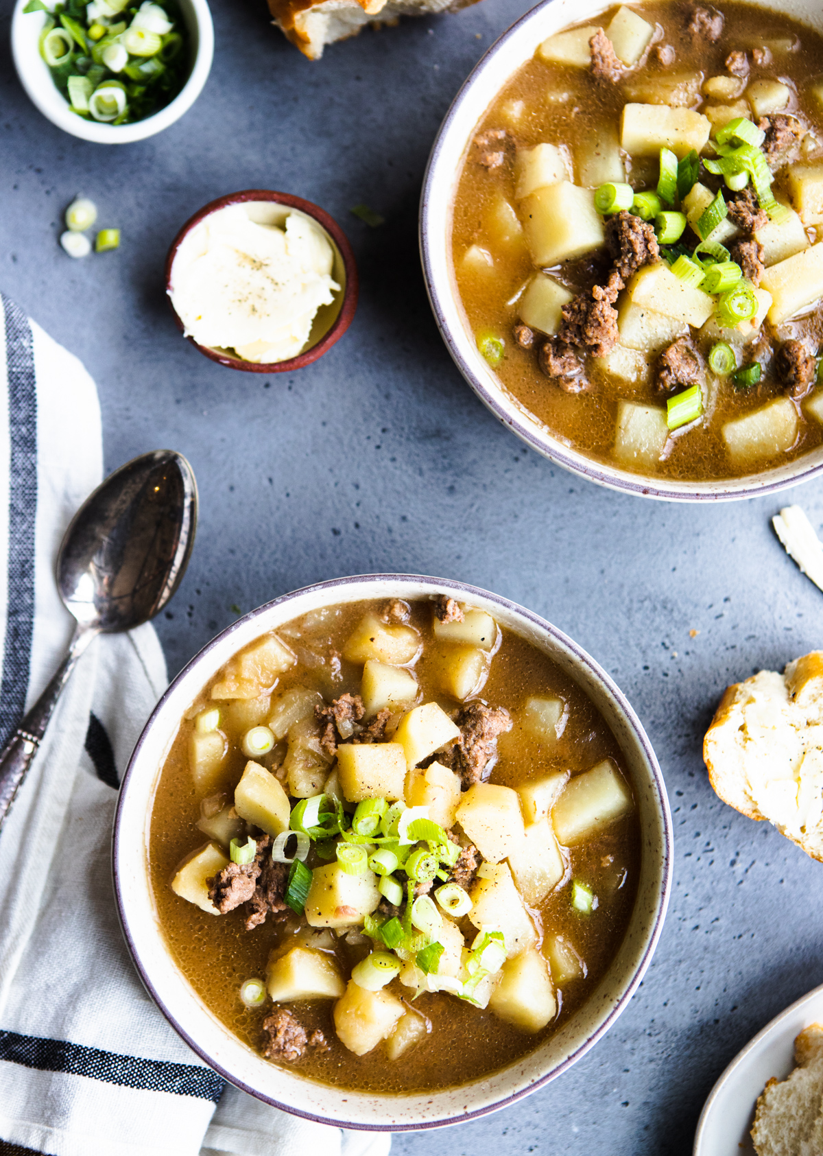 round soup bowls filled with hamburger potato soup and garnished with green onions 