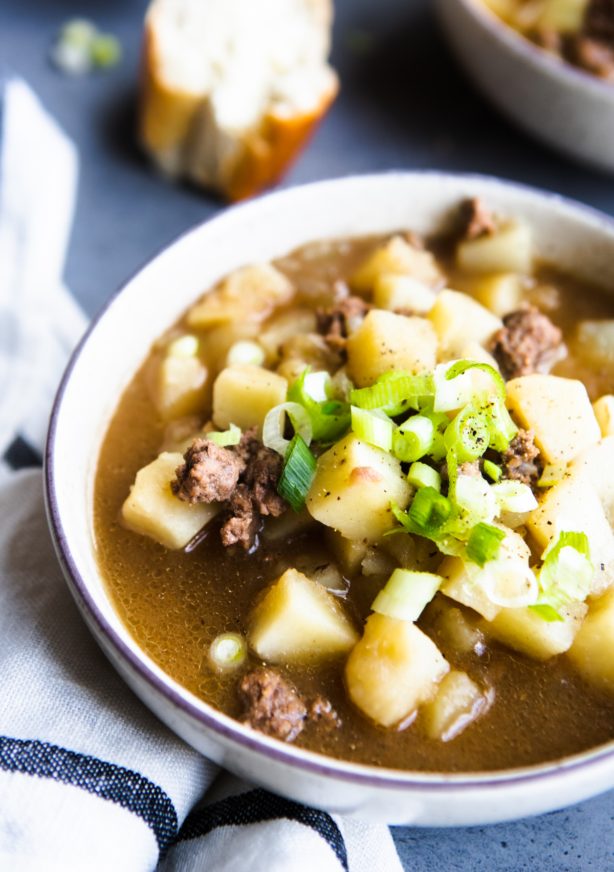 potato soup in a white soup bowl garnished with green onions 