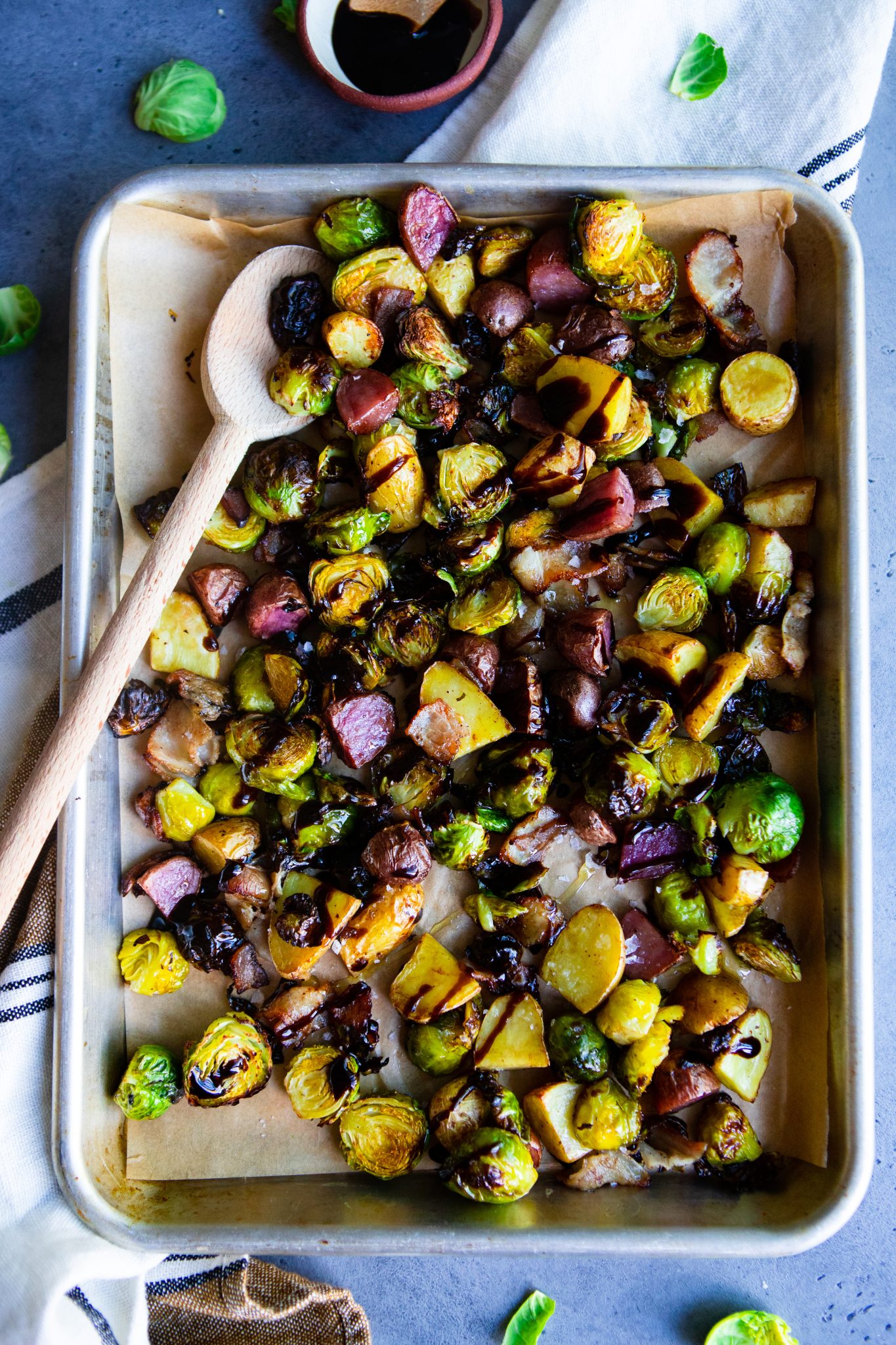 Brussel sprouts with bacon and balsamic on a sheet pan against a gray background 