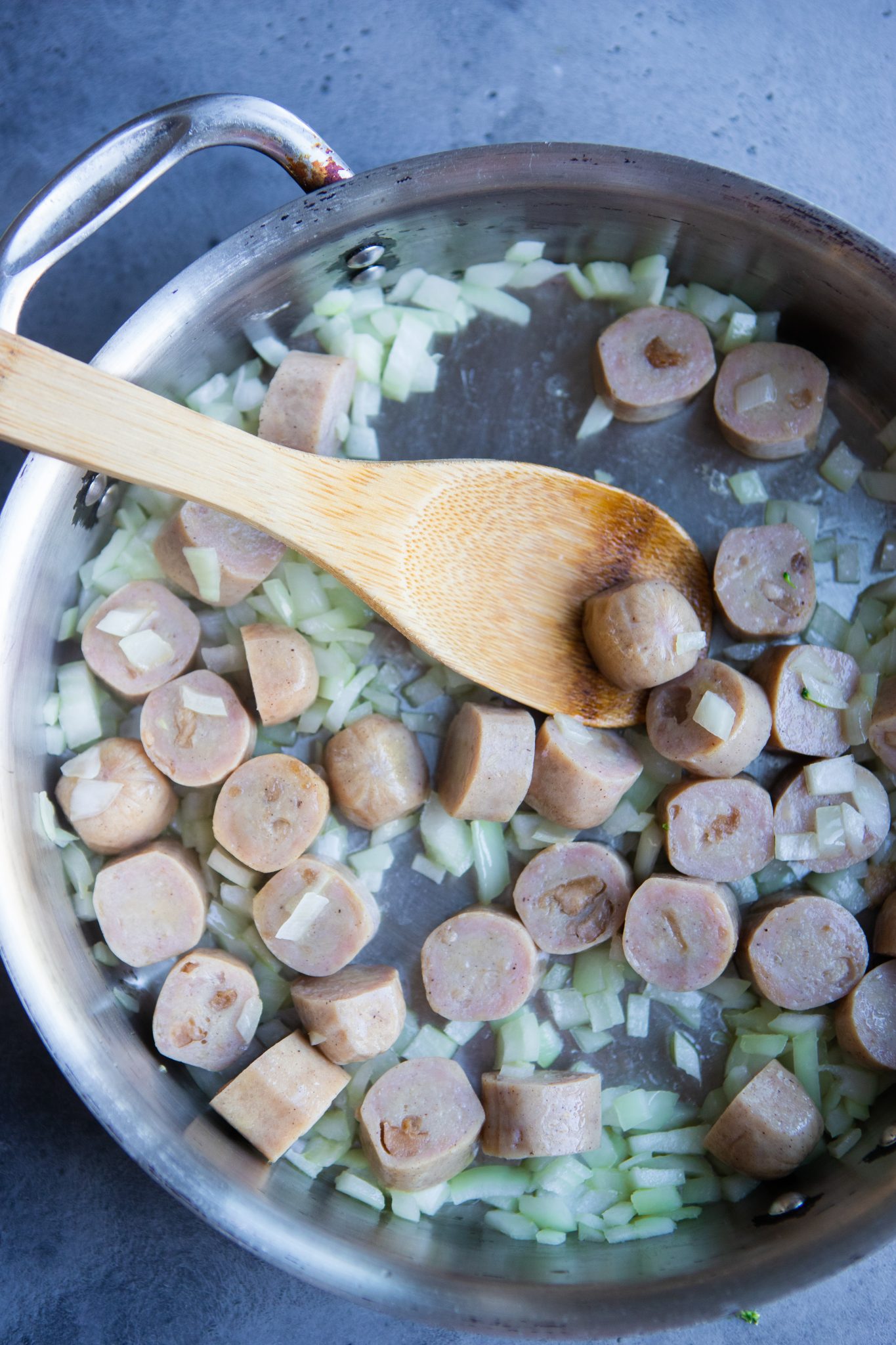 chicken apple sausage slices and onions being sautéed in a skillet