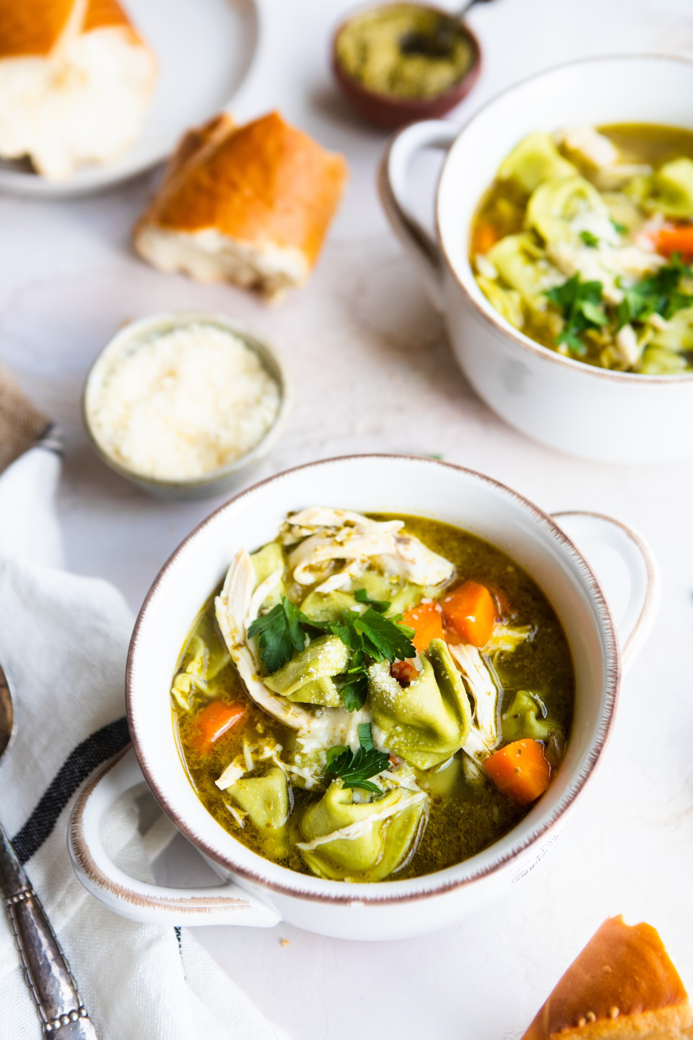 2 ceramic handled bowls filled with chicken tortellini soup 