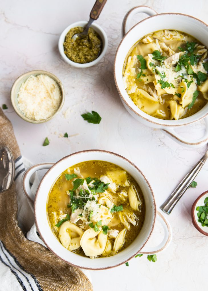 warm chicken noodle soup in a ceramic dish sprinkled with parmesan cheese and parsley