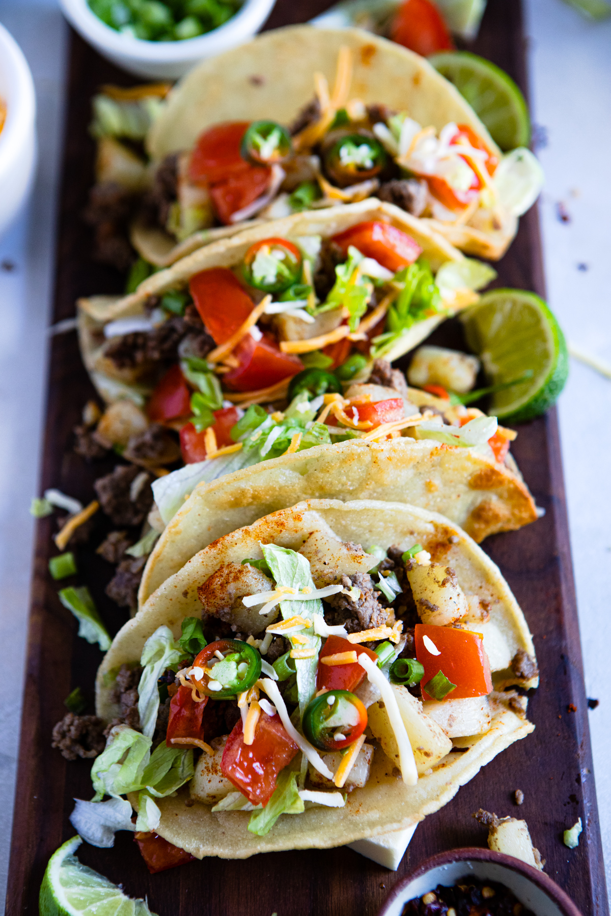 platter of tacos garnished with lettuce, tomatoes and jalapeno