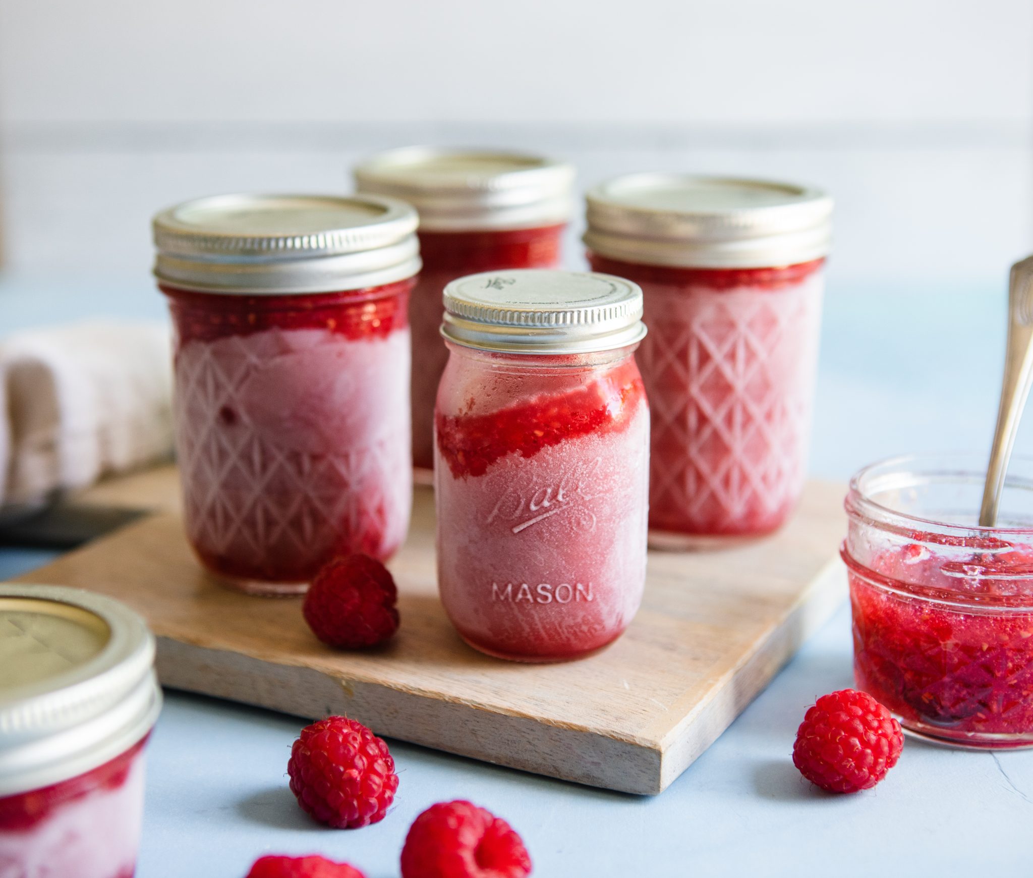 frozen jam in mason jars surrounded by fresh raspberries 