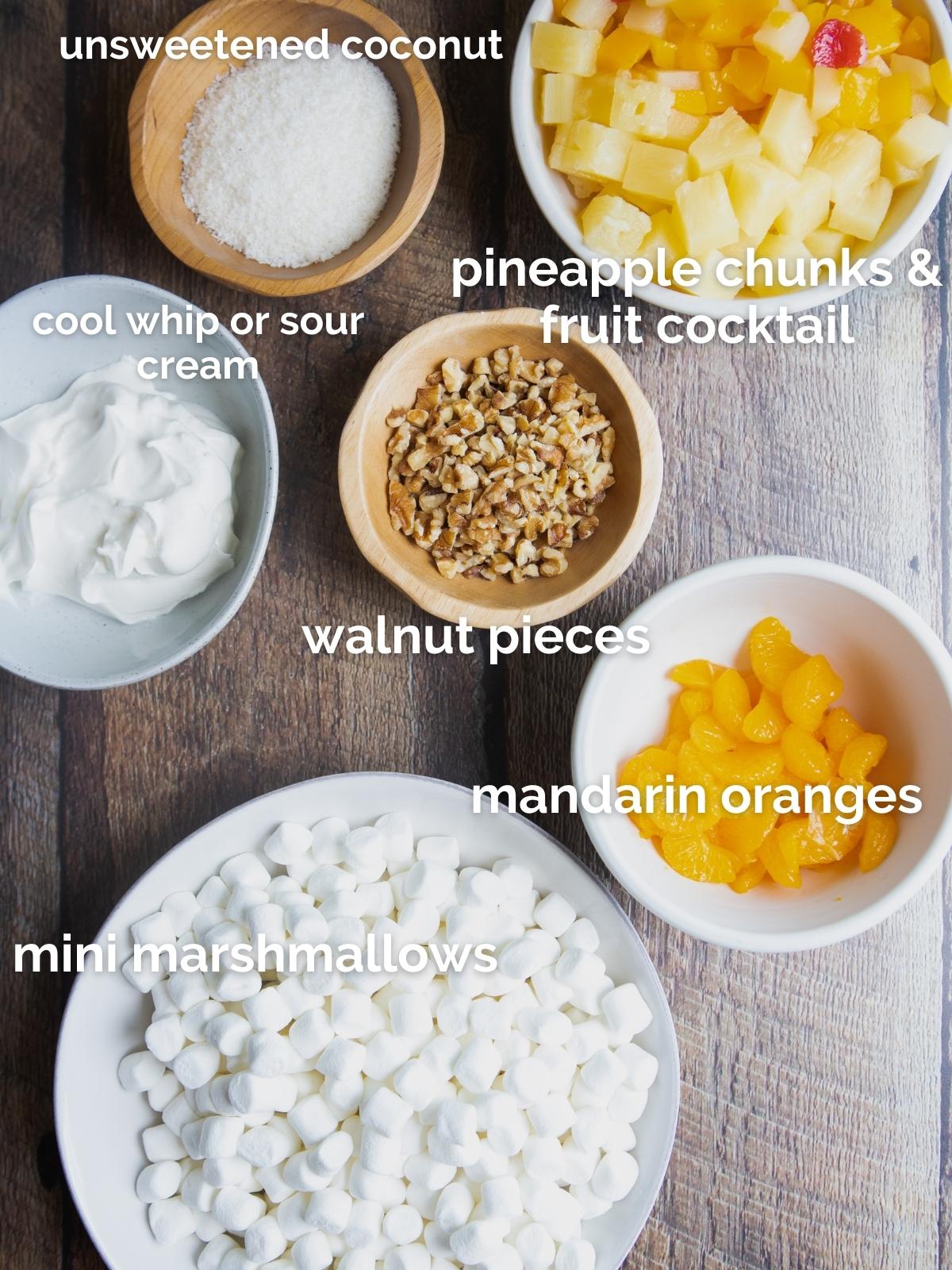 ingredients to make ambrosia fruit salad in little white and wood bowls